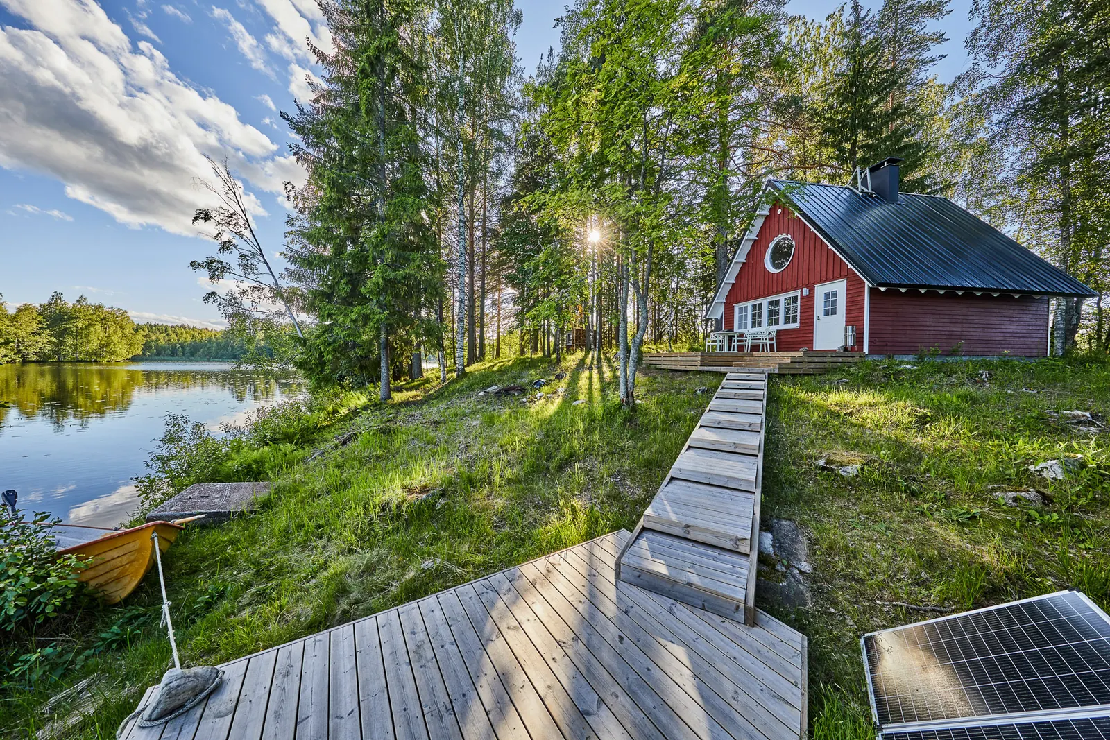 Rotes Sommerhaus zwischen Kiefern am Seeufer