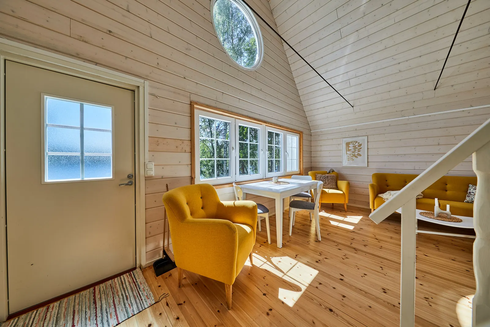 Wohnraum mit Eingangstür, Sesseln und Blick zum Esstisch